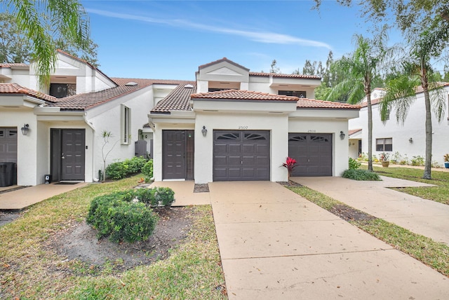 mediterranean / spanish-style house with concrete driveway, an attached garage, a tile roof, and stucco siding