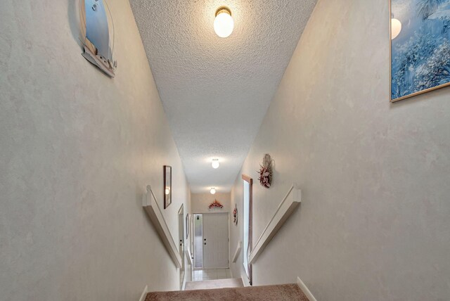 hall featuring a textured ceiling and stairs