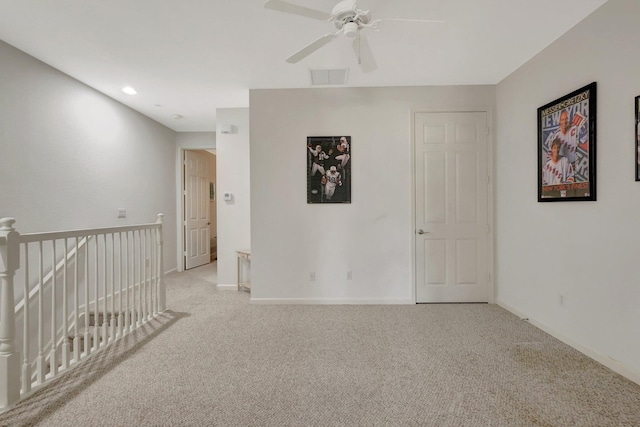 spare room with light carpet, ceiling fan, visible vents, and baseboards