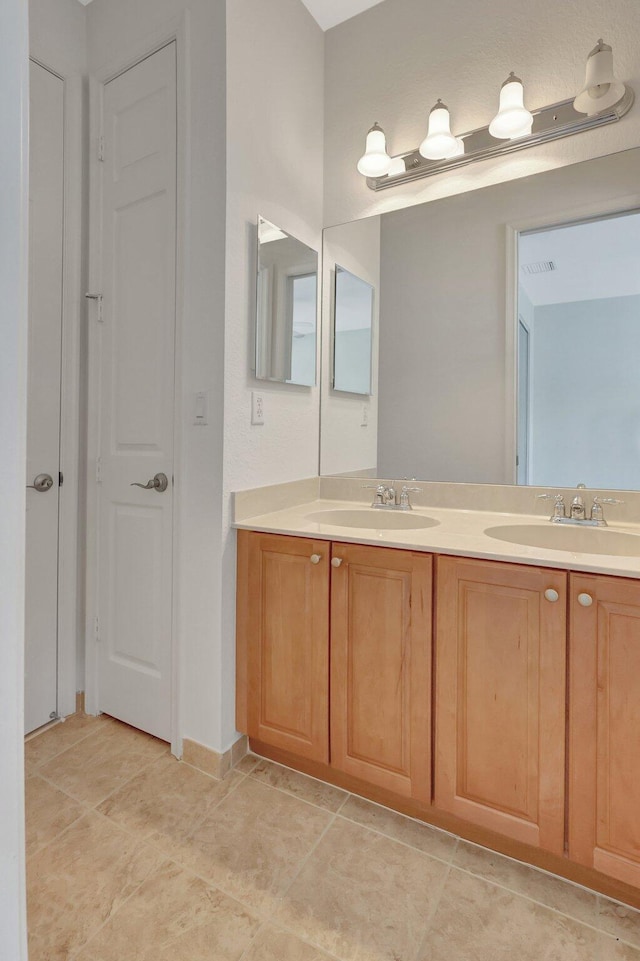 bathroom with double vanity, tile patterned flooring, a closet, and a sink