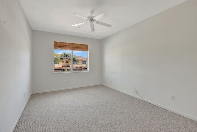 carpeted spare room featuring a ceiling fan and baseboards