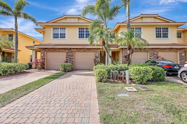 view of front of house featuring an attached garage, driveway, a tiled roof, and stucco siding