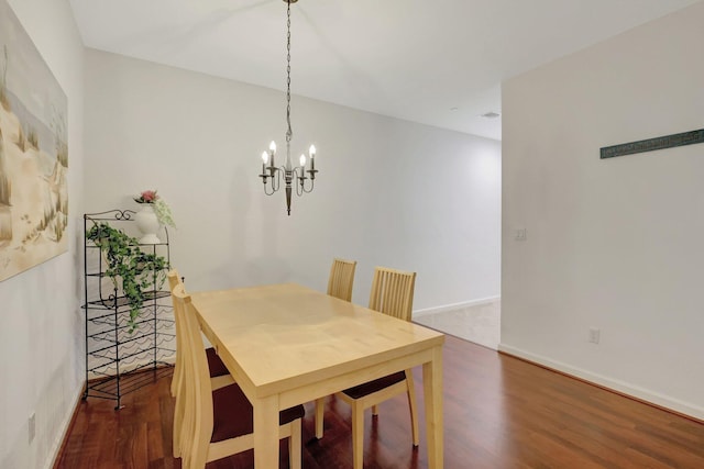 dining area featuring dark wood-style floors, baseboards, and an inviting chandelier