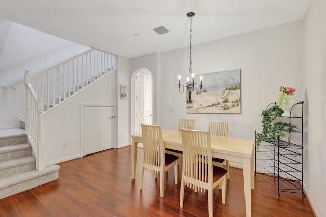 dining area featuring visible vents, arched walkways, stairway, wood finished floors, and a notable chandelier