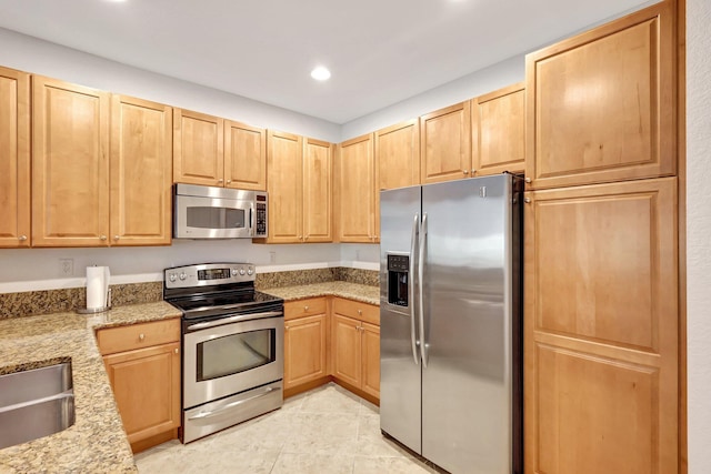 kitchen featuring stainless steel appliances, recessed lighting, light brown cabinets, and light stone counters