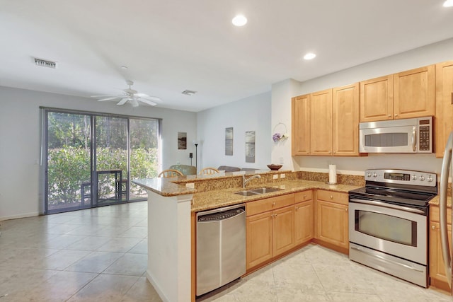 kitchen featuring visible vents, appliances with stainless steel finishes, a sink, light stone countertops, and a peninsula