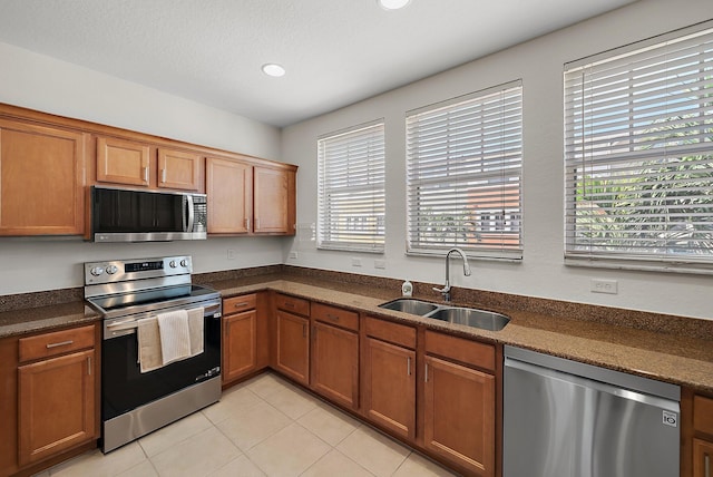 kitchen featuring dark countertops, brown cabinets, stainless steel appliances, and a sink