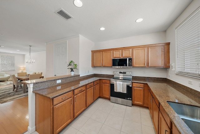 kitchen with a peninsula, visible vents, appliances with stainless steel finishes, and brown cabinetry