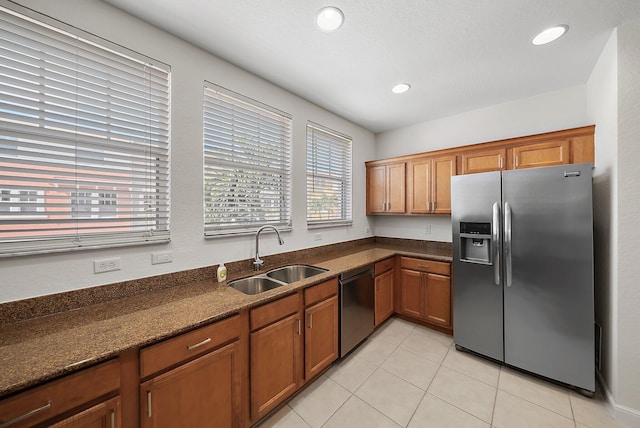 kitchen with brown cabinets, light tile patterned flooring, a sink, dishwasher, and stainless steel fridge with ice dispenser