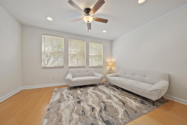 living room with light wood finished floors, baseboards, ceiling fan, crown molding, and recessed lighting