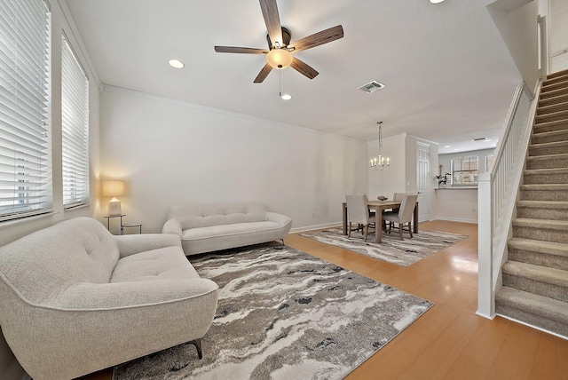 living area featuring recessed lighting, wood finished floors, visible vents, stairs, and ornamental molding