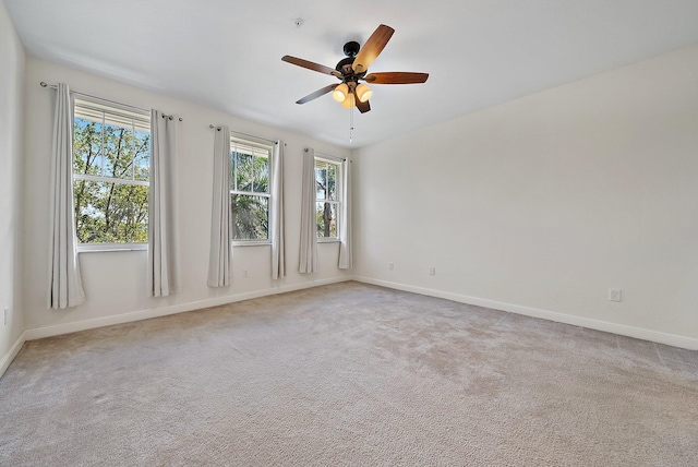 carpeted spare room featuring a ceiling fan, a healthy amount of sunlight, and baseboards