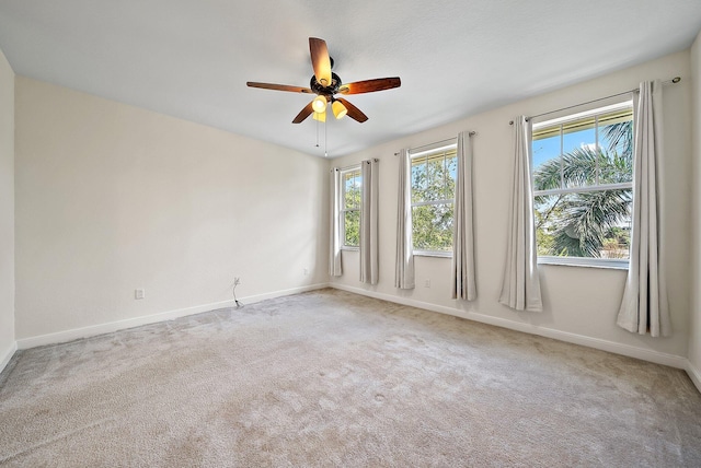 carpeted spare room with a ceiling fan and baseboards