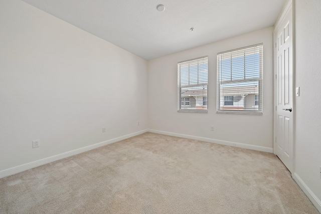 unfurnished room featuring baseboards and light colored carpet