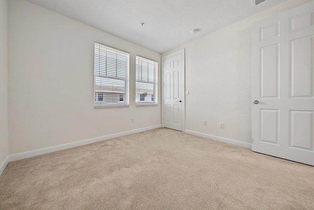 unfurnished room with light carpet and baseboards