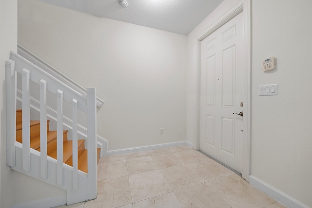 foyer entrance with marble finish floor, baseboards, and stairs