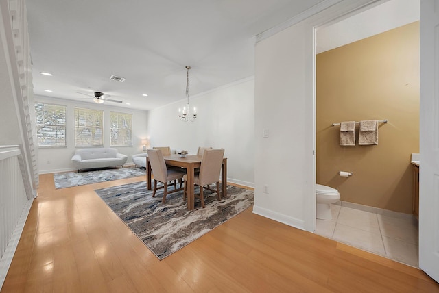 dining space featuring baseboards, visible vents, wood finished floors, and ceiling fan with notable chandelier