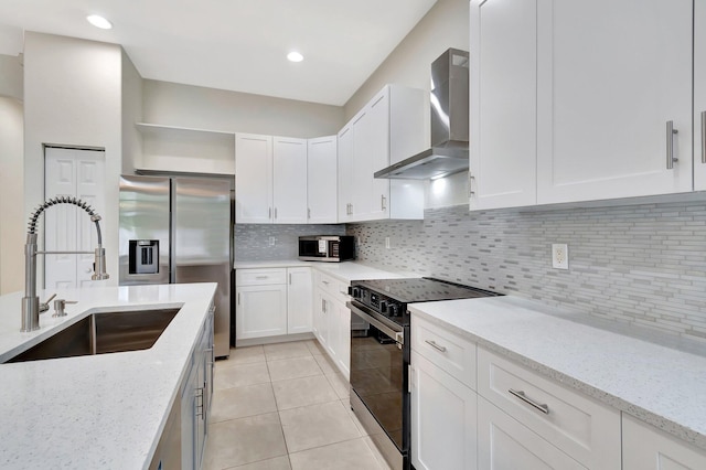 kitchen featuring wall chimney exhaust hood, white cabinets, a sink, and range with electric stovetop