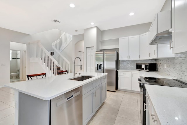 kitchen with light tile patterned floors, under cabinet range hood, stainless steel appliances, a sink, and visible vents