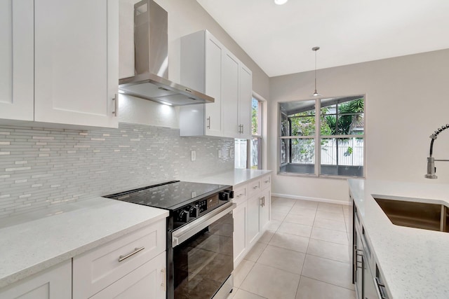 kitchen featuring range with electric cooktop, a sink, white cabinetry, wall chimney range hood, and tasteful backsplash