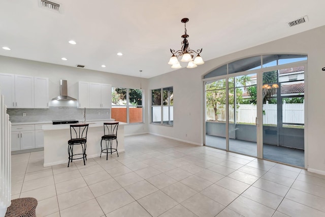 kitchen with wall chimney range hood, light tile patterned flooring, visible vents, and decorative backsplash