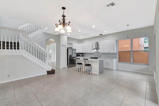 kitchen with stainless steel appliances, visible vents, decorative backsplash, white cabinets, and wall chimney range hood