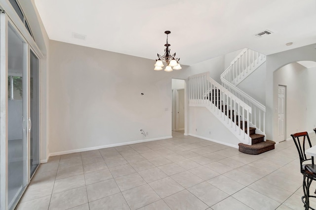 spare room featuring arched walkways, visible vents, baseboards, and stairs