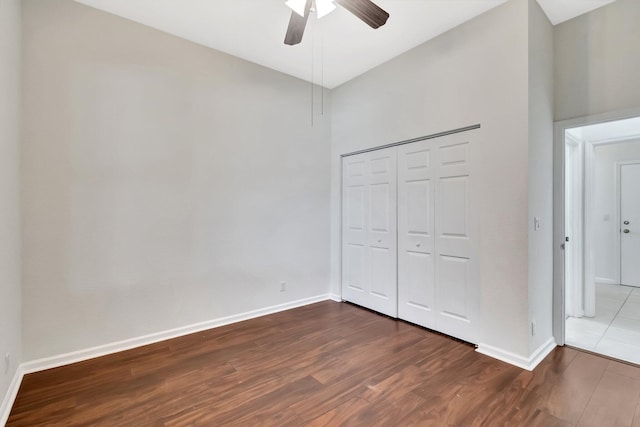 unfurnished bedroom with ceiling fan, baseboards, dark wood finished floors, and a closet