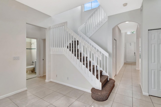 stairs featuring arched walkways, tile patterned flooring, and baseboards