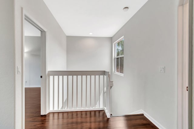 hallway with baseboards, an upstairs landing, and wood finished floors