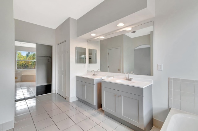 bathroom featuring a closet, two vanities, a sink, and tile patterned floors