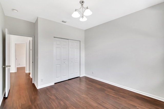 unfurnished bedroom with dark wood-type flooring, a closet, visible vents, and baseboards