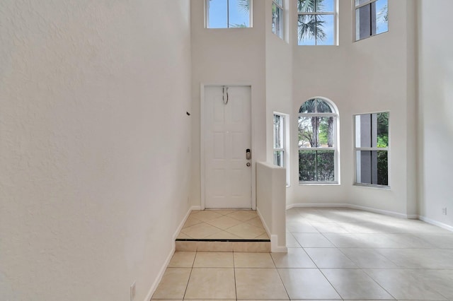 entrance foyer with a towering ceiling, baseboards, and light tile patterned floors