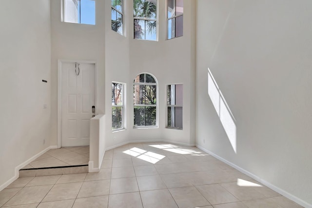 foyer featuring a towering ceiling, baseboards, and light tile patterned floors