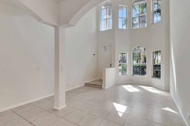 foyer entrance with a towering ceiling, baseboards, and light tile patterned floors