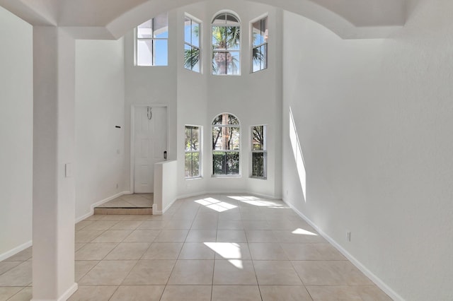 foyer with light tile patterned floors, arched walkways, and baseboards