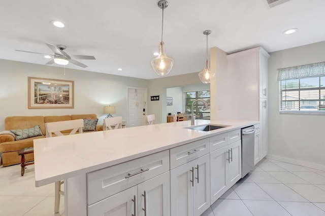 kitchen with a sink, white cabinets, open floor plan, hanging light fixtures, and stainless steel dishwasher