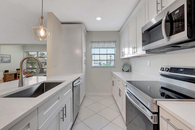 kitchen with a sink, white cabinetry, light countertops, appliances with stainless steel finishes, and hanging light fixtures