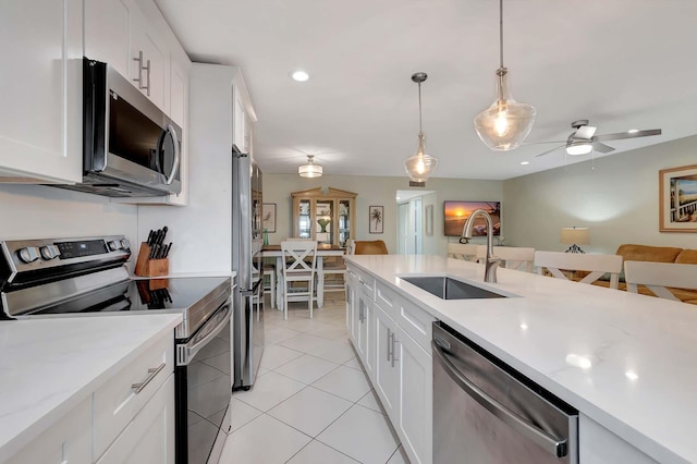 kitchen featuring hanging light fixtures, white cabinetry, stainless steel appliances, and a sink