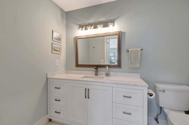 bathroom featuring toilet, baseboards, and vanity