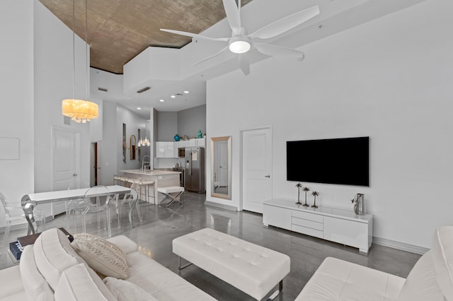 living area featuring baseboards, a high ceiling, visible vents, and a ceiling fan