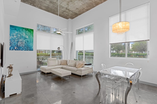 living room featuring baseboards, concrete floors, and a high ceiling