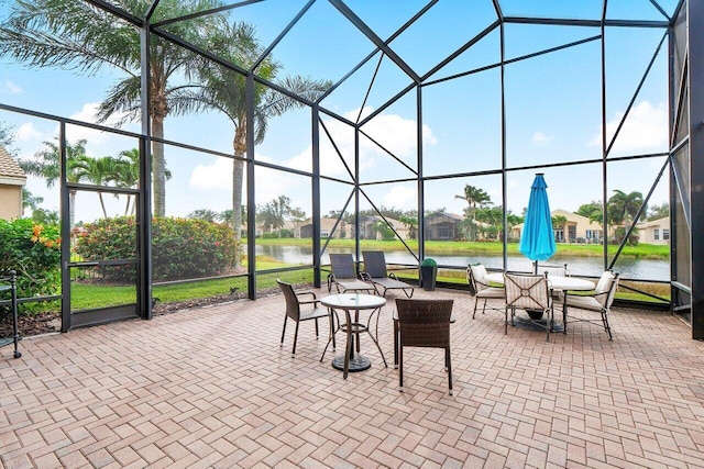 view of patio / terrace featuring a water view and glass enclosure