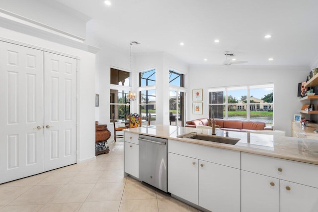 kitchen featuring white cabinets, decorative light fixtures, stainless steel dishwasher, a sink, and light tile patterned flooring