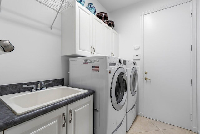 washroom featuring light tile patterned floors, washer and clothes dryer, a sink, and cabinet space