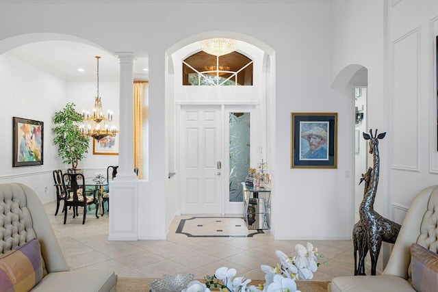 foyer entrance with crown molding, recessed lighting, an inviting chandelier, light tile patterned flooring, and ornate columns