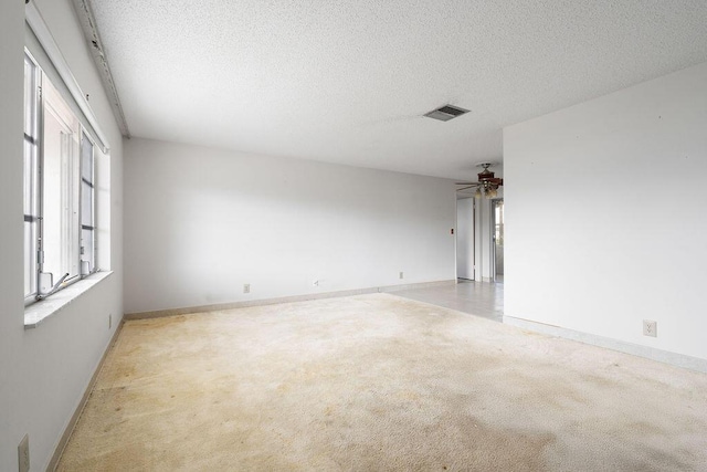 carpeted spare room with a ceiling fan, baseboards, and a textured ceiling