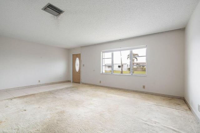 empty room featuring light carpet, a textured ceiling, visible vents, and baseboards