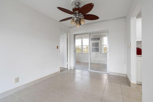 unfurnished room featuring light tile patterned floors, ceiling fan, baseboards, and a textured ceiling