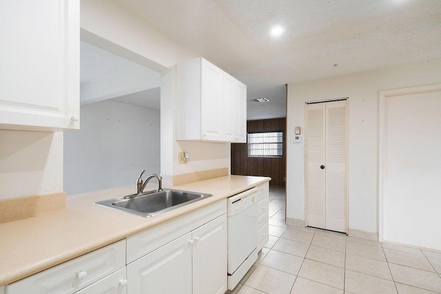 kitchen featuring light tile patterned floors, light countertops, white cabinets, a sink, and dishwasher